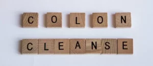 Nápis „Colon Cleanse“ vyskladaný z drevených písmenkových kociek – symbol očisty hrubého čreva a detoxikácie organizmu.