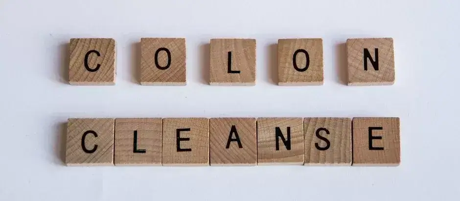 Nápis „Colon Cleanse“ vyskladaný z drevených písmenkových kociek – symbol očisty hrubého čreva a detoxikácie organizmu.