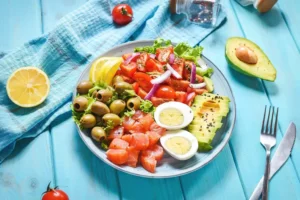 Farebný tanier so zeleninou, vajíčko, avokádom, olivami a údeným lososom – ukážka odporúčanej stravy pri diéte proti kandidóze.