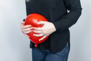 Žena si drží červený balón pred nafúknutým bruchom