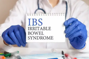 Lekár ukazuje tabuľku s nápisom „IBS Irritable Bowel Syndrome“ – ilustrácia funkčnej poruchy čriev – IBS a jej príznakov.