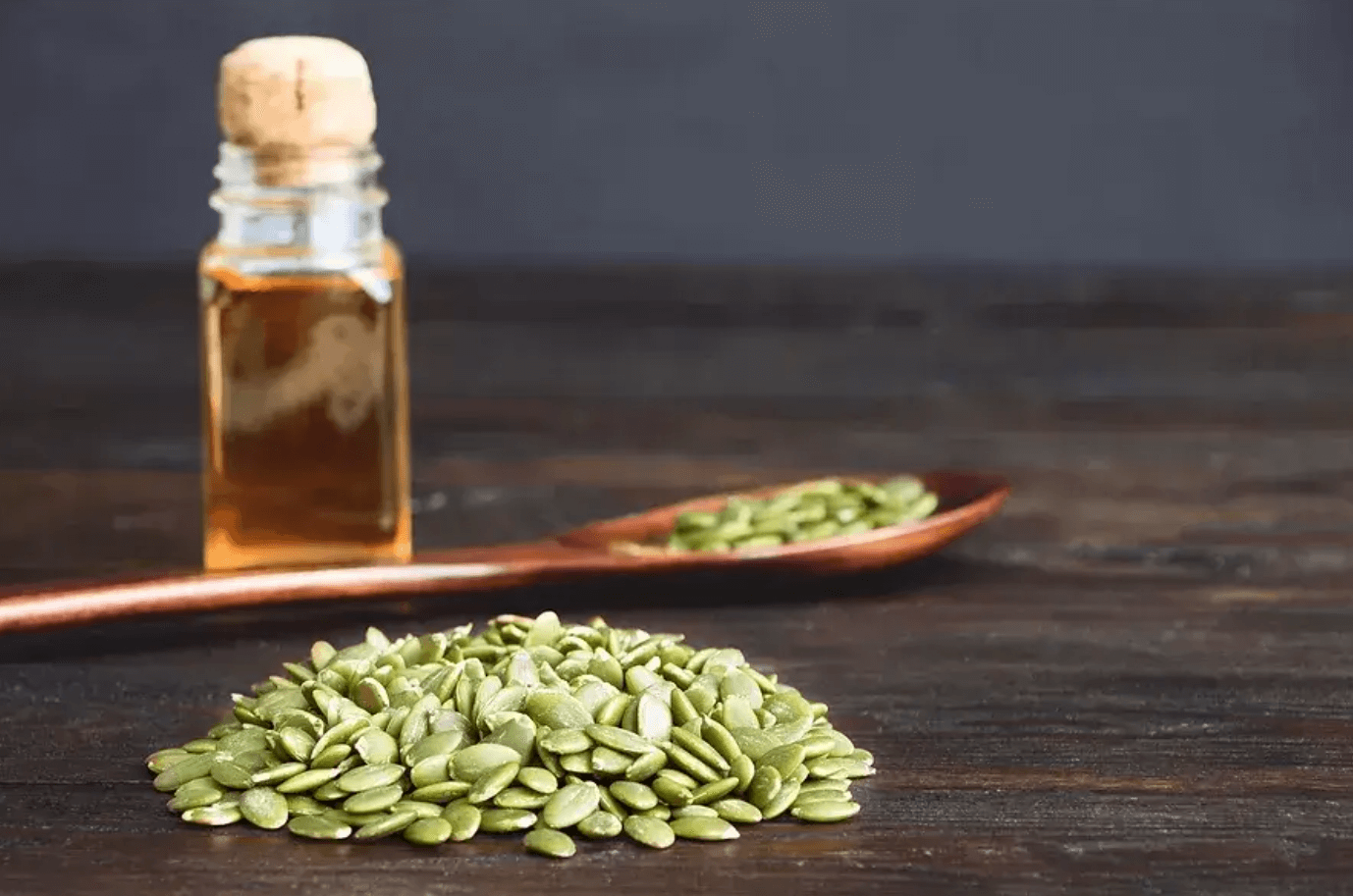 Tekvicové semienka a fľaštička s olejom na drevenom stole – prírodné liečivé rastliny s antiparazitárnym účinkom.