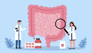 Ilustrácia ľudského čreva v popredí, dvaja lekári skúmajú tráviaci trakt lupou a zdravotníckymi pomôckami – podpora zdravia črevného systému a mikrobiomu.