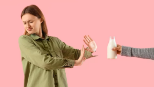 Žena odmietajúca fľašu mlieka – ilustrácia laktózovej intolerancie, citlivosť na mliečny cukor, mliečne výrobky a ich vplyv na trávenie.